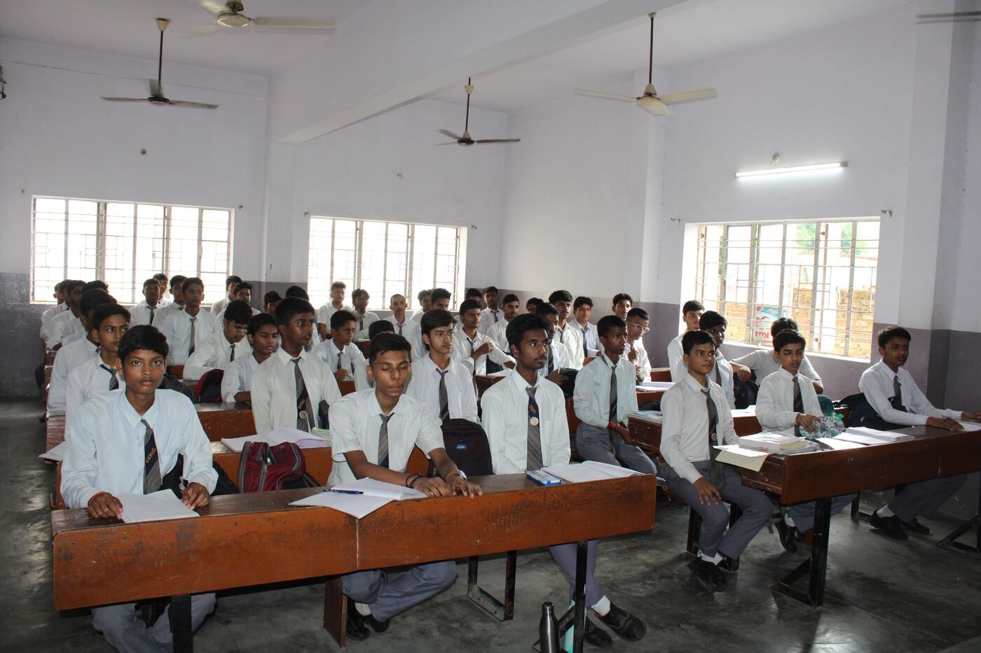 Senior boys seated at benches during a class at SVM Inter College